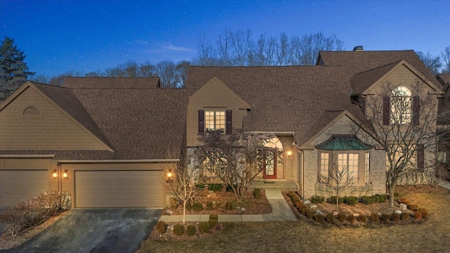 view of front of property featuring an attached garage, driveway, and a shingled roof