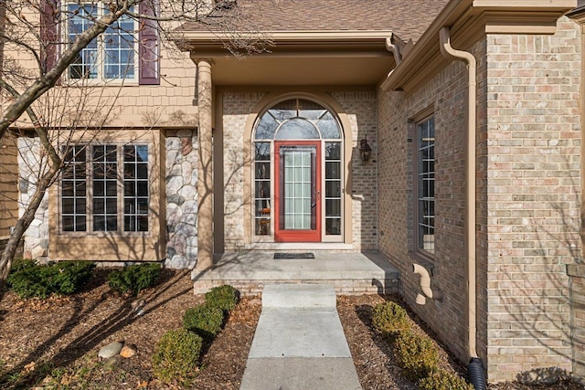 property entrance featuring brick siding and roof with shingles