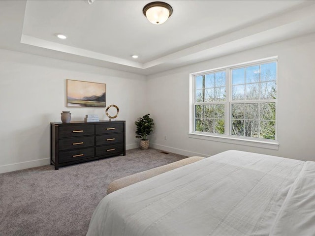 bedroom featuring a tray ceiling, light colored carpet, and baseboards