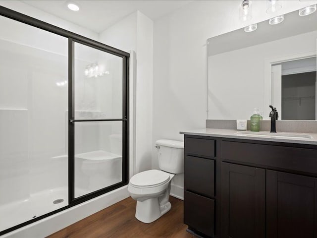 bathroom featuring vanity, a shower stall, toilet, and wood finished floors