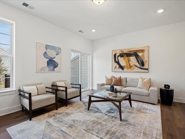 living area with a wealth of natural light, visible vents, and wood finished floors