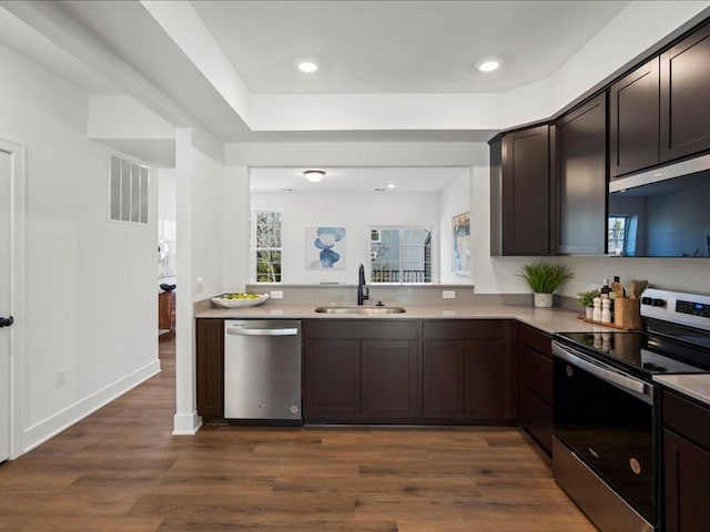 kitchen featuring visible vents, a sink, stainless steel appliances, dark brown cabinetry, and light countertops