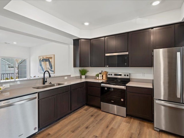 kitchen with a sink, stainless steel appliances, dark brown cabinets, and light countertops