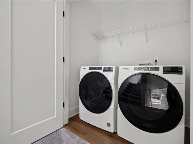 clothes washing area with laundry area, washer and dryer, and wood finished floors