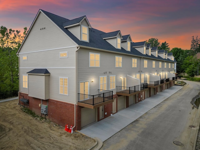 back of house at dusk featuring an attached garage