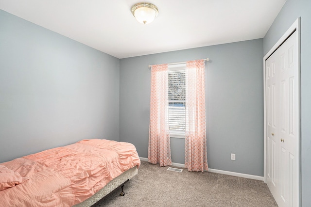 bedroom featuring a closet, carpet flooring, visible vents, and baseboards