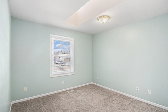 carpeted empty room with a skylight, visible vents, and baseboards