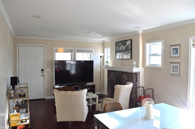 living area featuring dark wood finished floors, a stone fireplace, crown molding, and baseboards