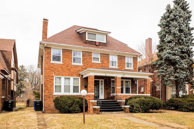 traditional style home with brick siding, covered porch, and a front yard