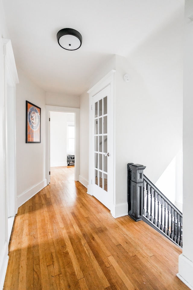 hall with baseboards and wood-type flooring