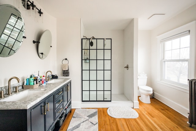 bathroom with toilet, wood finished floors, walk in shower, and a sink