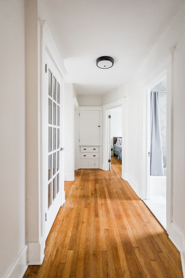 hallway featuring light wood-type flooring and baseboards