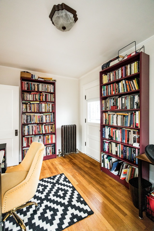 living area featuring ornamental molding, radiator, and wood finished floors