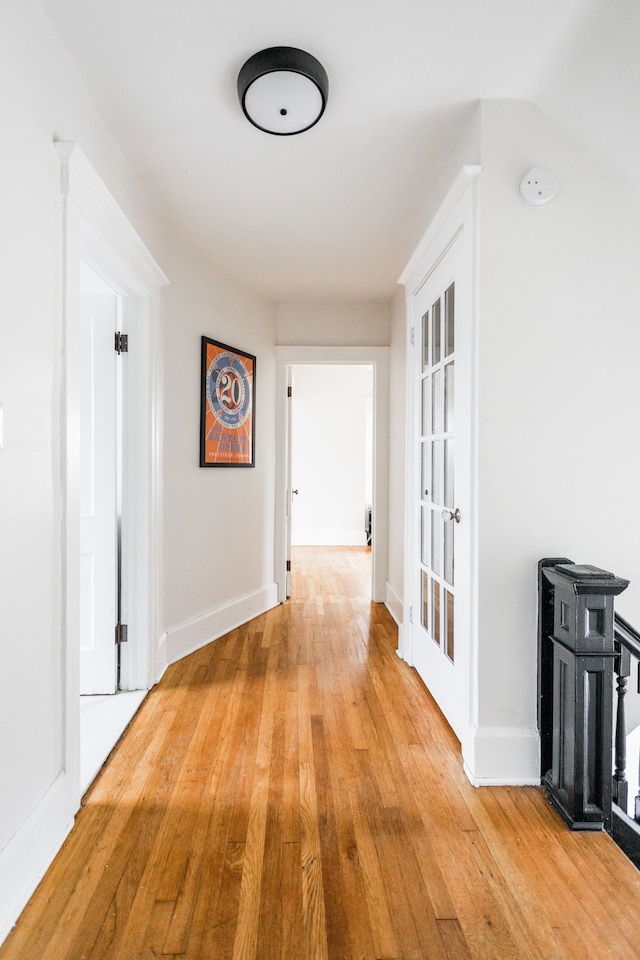 hall featuring light wood-type flooring and baseboards