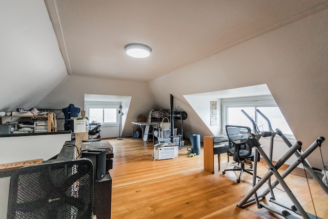 exercise room featuring vaulted ceiling and light wood finished floors