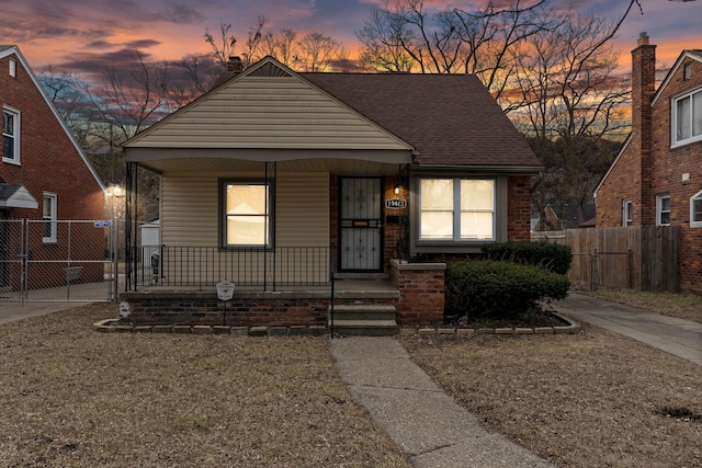 bungalow-style home with a gate, a porch, roof with shingles, and fence