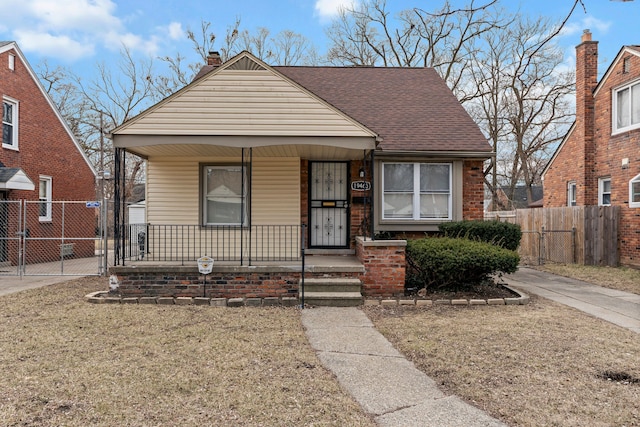 bungalow with a gate, a porch, roof with shingles, and fence