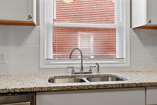 kitchen featuring white cabinetry, dishwasher, light stone countertops, and a sink