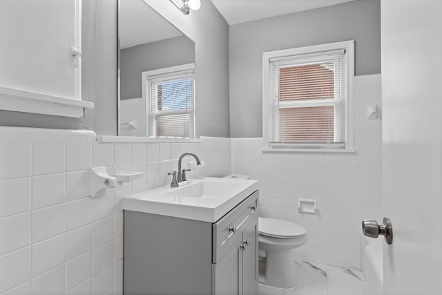 bathroom with vanity, a wainscoted wall, tile walls, toilet, and marble finish floor