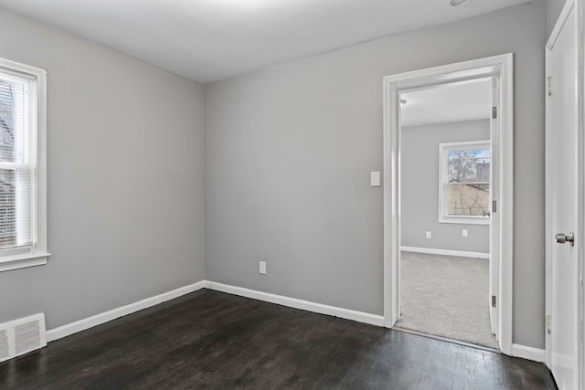 spare room featuring visible vents, dark wood-type flooring, and baseboards