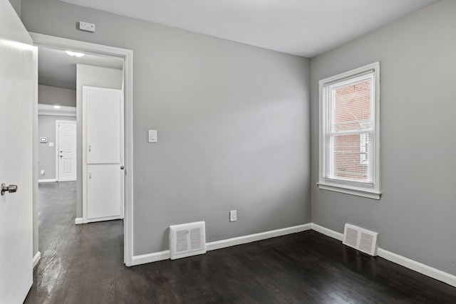 empty room featuring visible vents, baseboards, and dark wood-style flooring