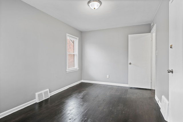 unfurnished room with dark wood finished floors, visible vents, and baseboards