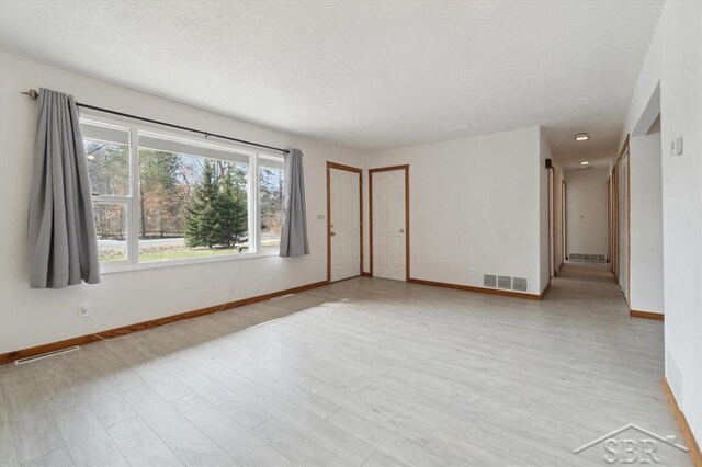 unfurnished room with visible vents, baseboards, a textured ceiling, and light wood-style flooring