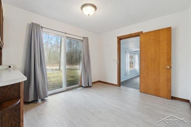 unfurnished room featuring light wood-style flooring and baseboards