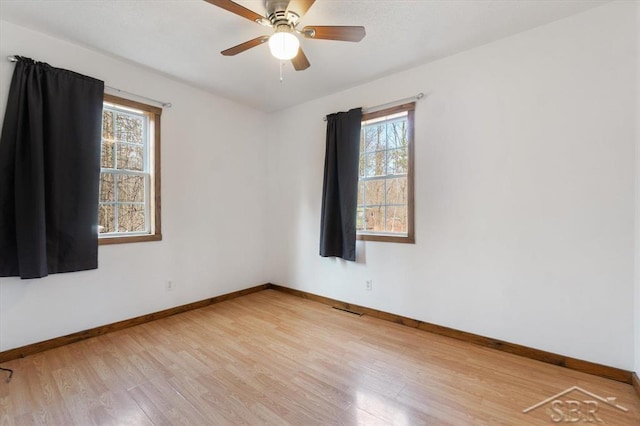 empty room with visible vents, ceiling fan, light wood-type flooring, and baseboards