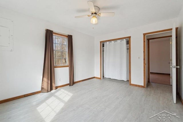 unfurnished bedroom with a closet, baseboards, electric panel, and light wood-style floors