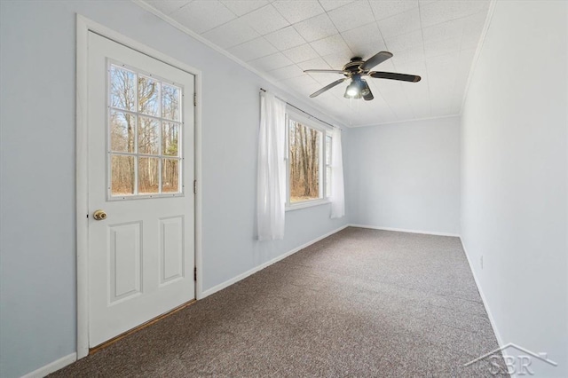 empty room featuring ceiling fan, baseboards, carpet floors, and ornamental molding