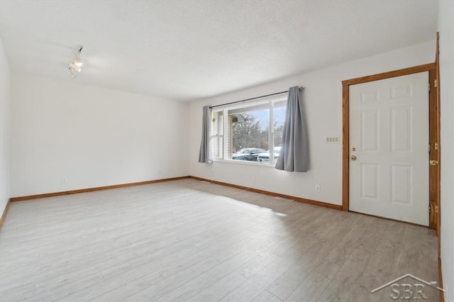 unfurnished room with baseboards, a textured ceiling, and wood finished floors