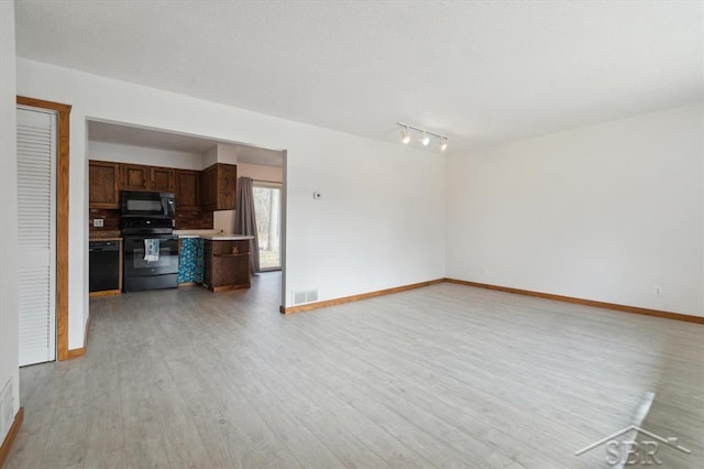 unfurnished living room featuring visible vents, baseboards, light wood finished floors, and a textured ceiling