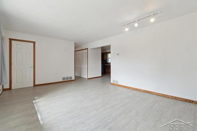 empty room featuring visible vents, baseboards, and light wood-style flooring