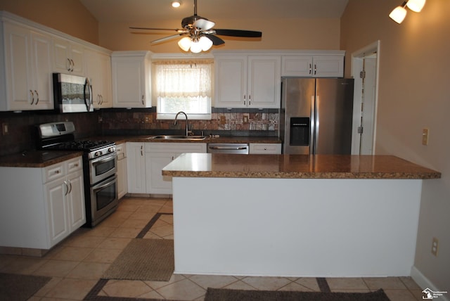 kitchen with a sink, dark countertops, tasteful backsplash, appliances with stainless steel finishes, and light tile patterned floors