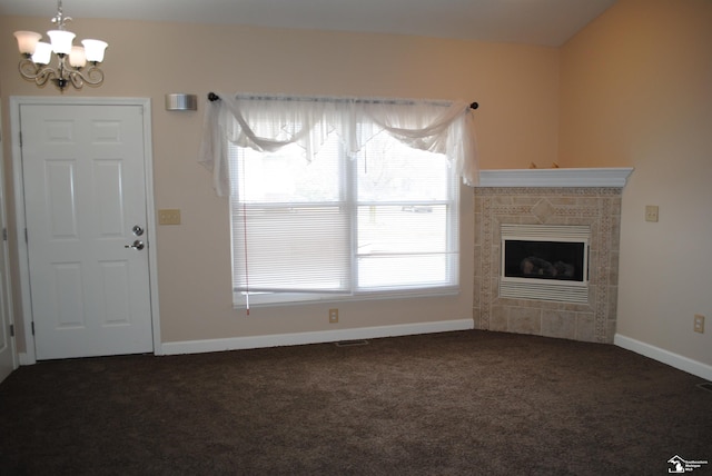 unfurnished living room featuring visible vents, baseboards, a tiled fireplace, a notable chandelier, and carpet flooring