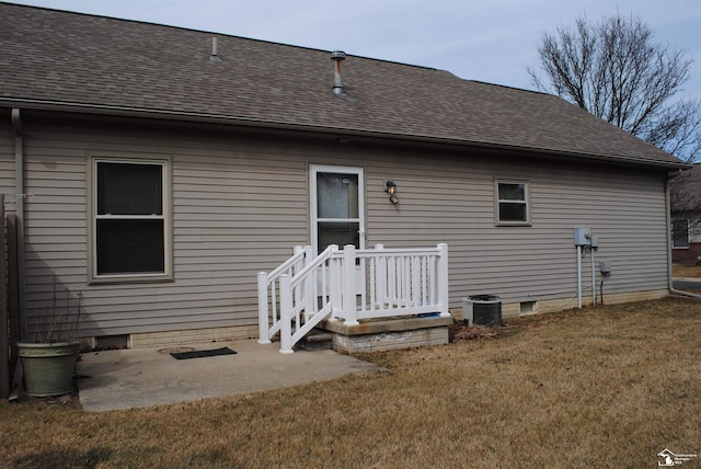 rear view of house with a shingled roof, a patio area, a lawn, and crawl space