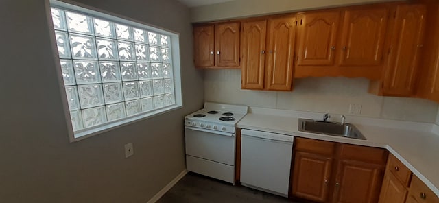 kitchen featuring white appliances, brown cabinetry, baseboards, a sink, and light countertops