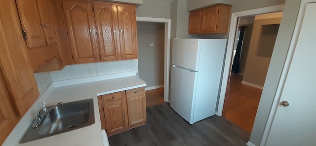 kitchen with a sink, light countertops, dark wood-style flooring, and freestanding refrigerator