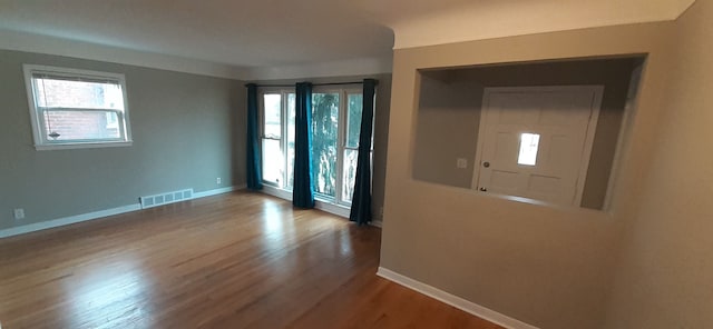 interior space featuring visible vents, baseboards, a healthy amount of sunlight, and wood finished floors