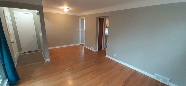 unfurnished room featuring light wood-style floors, visible vents, and baseboards