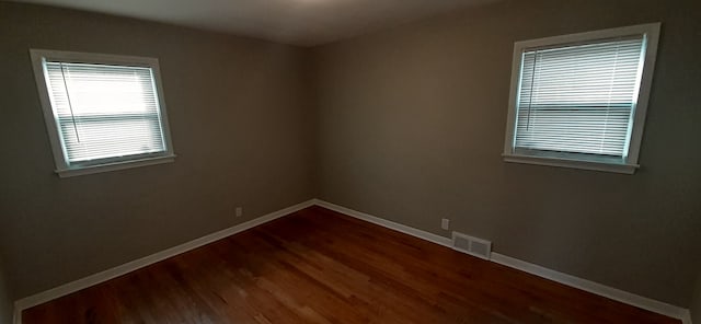 spare room with visible vents, baseboards, and wood finished floors