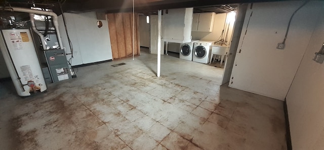 unfinished below grade area with a sink, heating unit, water heater, and washer and clothes dryer