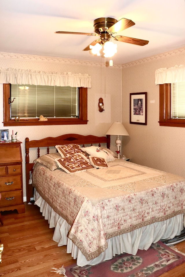 bedroom featuring wallpapered walls, ceiling fan, and wood finished floors