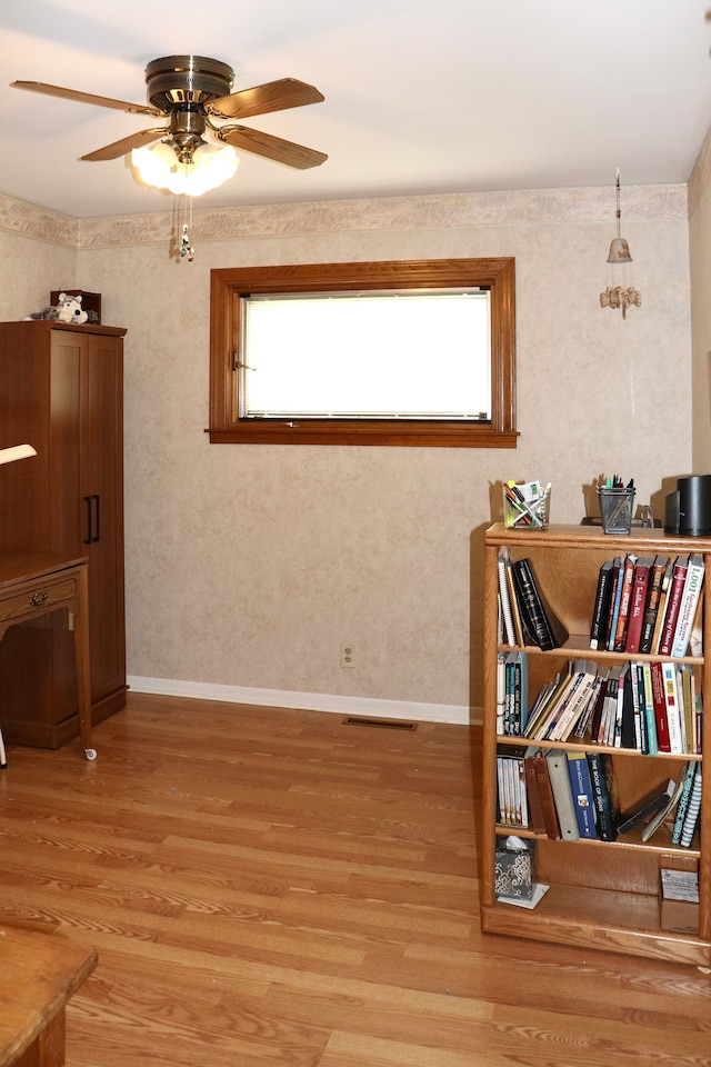 interior space featuring light wood finished floors, visible vents, baseboards, and ceiling fan