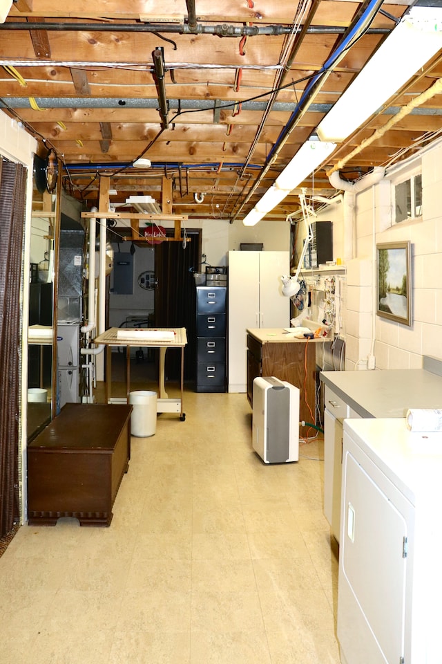 unfinished basement with washer / dryer, concrete block wall, electric panel, and freestanding refrigerator