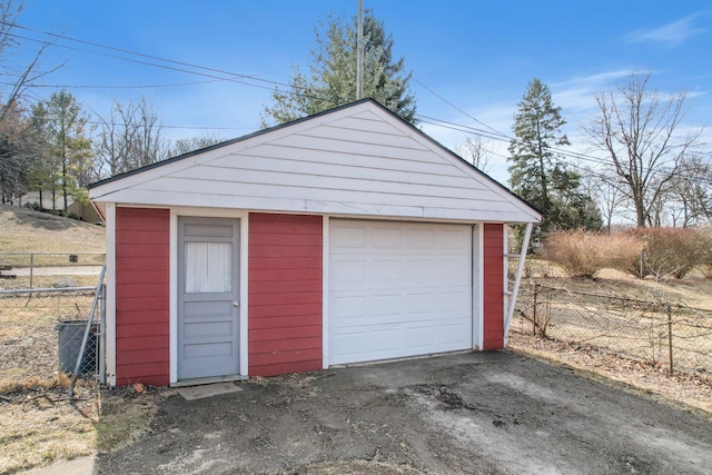 detached garage with dirt driveway and fence