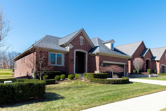 view of front of home featuring brick siding, an attached garage, concrete driveway, and a front yard