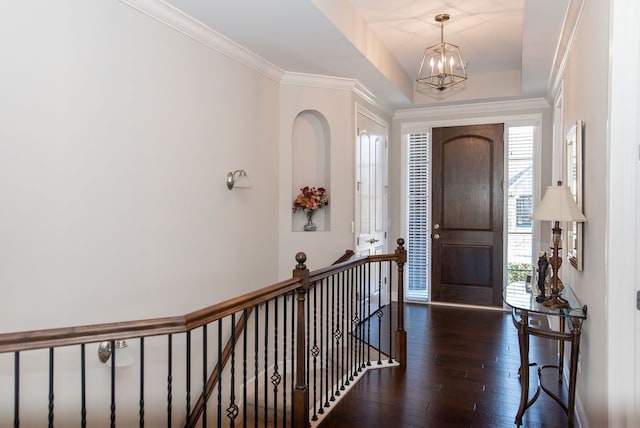 foyer with crown molding, a notable chandelier, plenty of natural light, and wood-type flooring