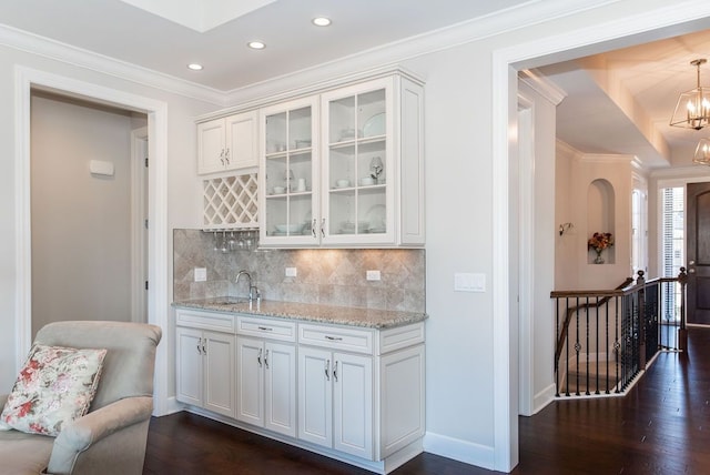 bar featuring baseboards, an inviting chandelier, dark wood-style flooring, ornamental molding, and tasteful backsplash